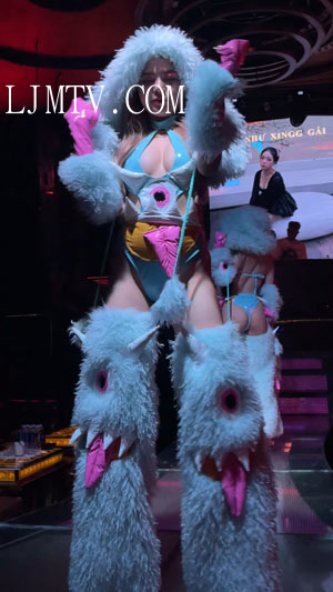 穿着夸张的毛绒外装内穿蓝色漆皮高叉泳装的热舞美女